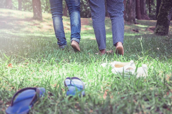 자연 정원에서 잔디에 걷는 남자와 커플 여성. 잔디 위를 걷는 부부의 발. 여행, 자연, 휴식. — 스톡 사진