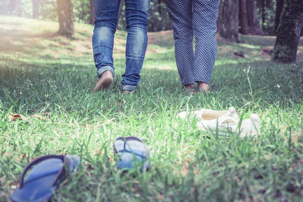 자연 정원에서 잔디에 걷는 남자와 커플 여성. 잔디 위를 걷는 부부의 발. 여행, 자연, 휴식. — 스톡 사진