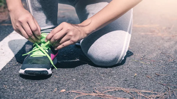 Le donne legano la catena di scarpe da jogging. Sulla passerella. esercizio, corsa, buona salute, rilassarsi . — Foto Stock