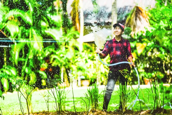 Asiatische Frauen verwenden Schlauchgarten, um Zitronengras im Gemüsegarten zu gießen. — Stockfoto
