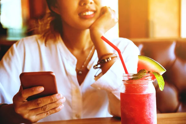 Asyalı kadın arkanıza yamave meyve içmek dinlenmek. Ve telefon tutuyor..