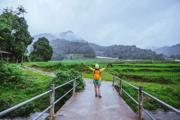 Asijské ženy cestují přírodou. Když si vyfotíte fotografii z rýžového pole, odpočiňte si na mostě na Ban Mae Klang Luang v období dešťů.. — Stock fotografie