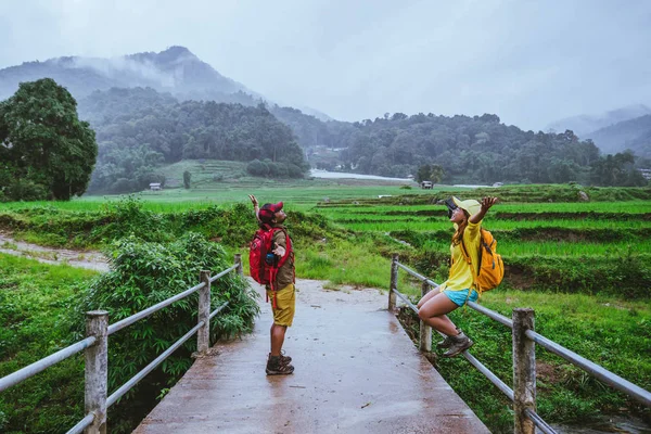 Amante asiático homem asiático mulheres viajar natureza. Caminhando uma foto do campo de arroz e parar fazer uma pausa relaxar na ponte na proibição mae klang luang na estação chuvosa . — Fotografia de Stock