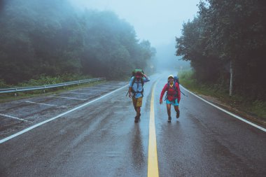 Sevgili Asyalı erkek ve Asyalı kadınlar doğa seyahat. Yol güzergahıüzerinde yürüyün. mutlu bir şekilde doğa seyahat. Sisli yağmurun ortasında. yağmur mevsiminde.