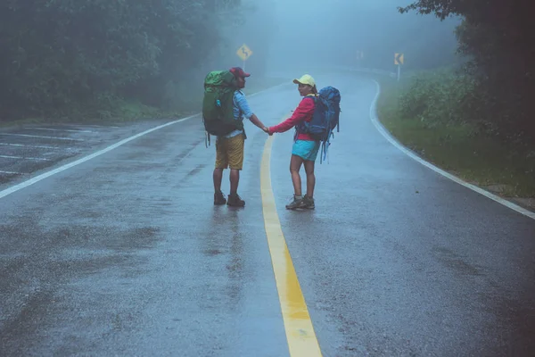 Amante del hombre asiático y las mujeres asiáticas viajan naturaleza. Camina por la ruta del camino. viajando por la naturaleza felizmente. Entre la niebla lluviosa. en la temporada de lluvias . — Foto de Stock