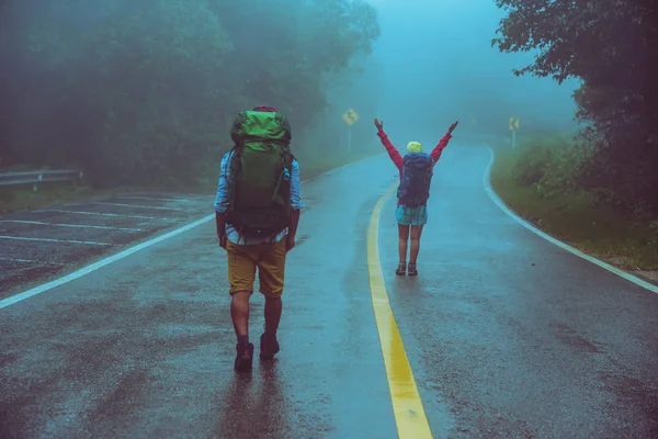 Sevgili Asyalı erkek ve Asyalı kadınlar doğa seyahat. Yol güzergahıüzerinde yürüyün. mutlu bir şekilde doğa seyahat. Sisli yağmurun ortasında. yağmur mevsiminde.