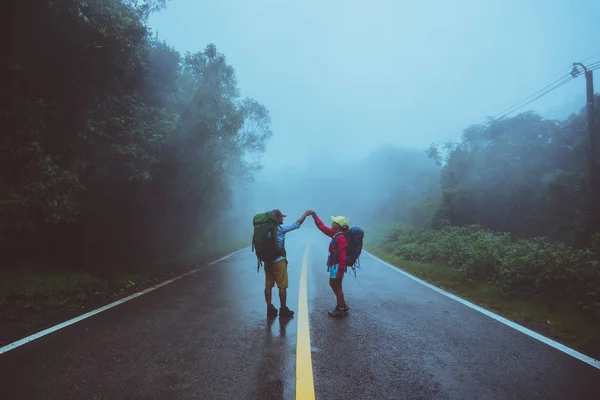 Älskare asiatiska mannen och asiatiska kvinnor reser naturen. Gå på väg rutten. reser naturen glatt. Mitt i dimman regnigt. under regnperioden. — Stockfoto