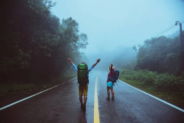 Amoureux homme asiatique et les femmes asiatiques voyagent nature. Marchez sur la route. voyageant la nature joyeusement. Dans la brume pluvieuse. en saison des pluies . — Photo