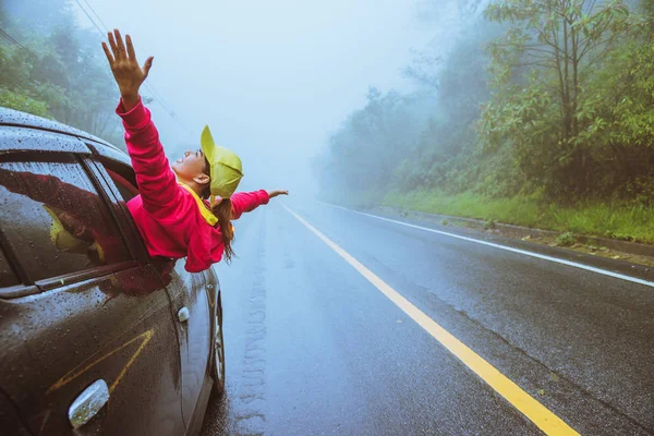 Asiatiska kvinnor reser slappna av på semestern. köra en bil som reser glatt. Mitt i dimman regnigt. — Stockfoto