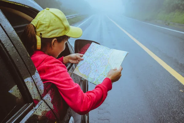 Asian women travel relax in the holiday. Traveling by car park. View map for Nature tours during the rainy season. — Stock Photo, Image