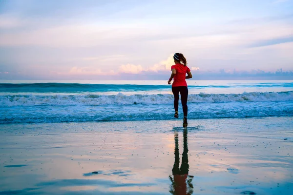 Девушка бегает трусцой по пляжу утром. Relax and happy with running on the sea. летом — стоковое фото