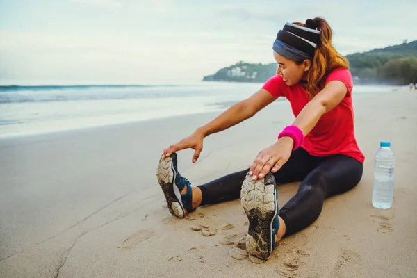 Mulheres asiáticas jogging treino na praia. Sente-se na praia fitness relaxar com pernas esticadas e braço esticado. A correr na praia. viagem Tailândia, exercício . — Fotografia de Stock