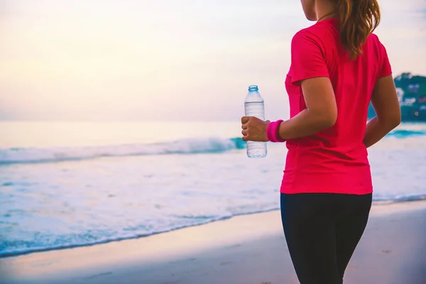 Donne asiatiche che fanno jogging allenamento sulla spiaggia al mattino. Rilassatevi con la passeggiata sul mare e l'acqua potabile dalle bottiglie di plastica. spiaggia, sport, esercizio fisico, viaggi Thailandia . — Foto Stock