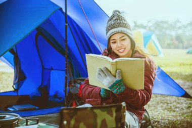 Asyalı kadın tatilde kamp dinlenmek seyahat. Dağda kamp. otur, sandalyede bir kitap oku. eğitim, kitap okumak, kitap okumak, not yazmak, günlük.