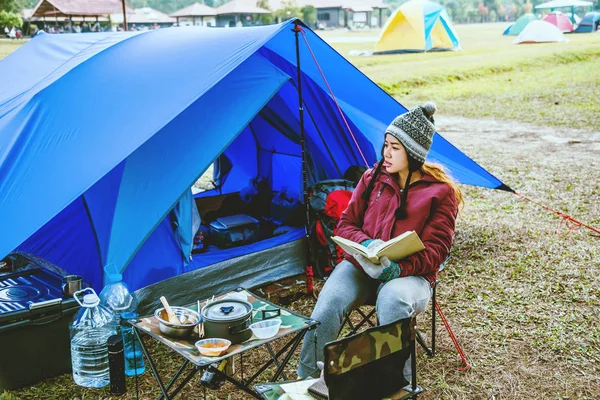 Aziatische vrouw reizen ontspannen kamperen in de vakantie. Kamperen op de berg. zitten ontspannen Lees een boek in de stoel. onderwijs, lees een boek, boek, schrijf een notitie, dagboek. — Stockfoto
