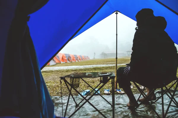 Viagem homem asiático relaxar no feriado. acampar na Montanha. sente-se relaxar na cadeira. Na atmosfera chuva cair nevoeiro para baixo. camping, campo, Floresta, barraca, na natureza, outdoor, feriado, relaxar, viajar, verão, viajar Tailândia . — Fotografia de Stock