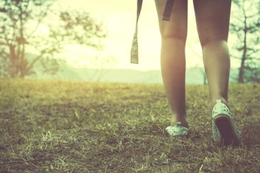 Kız bacakları çimenlerin üzerinde tatilde yürüyor. Kız doğaya seyahat ediyor. Seyahat rahatlayın. Dağ, Sırt Çantası, açık, tatil, dinlenmek, seyahat Tayland.