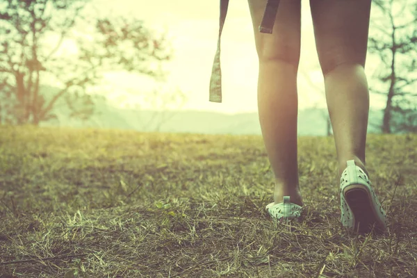 Kız bacakları çimenlerin üzerinde tatilde yürüyor. Kız doğaya seyahat ediyor. Seyahat rahatlayın. Dağ, Sırt Çantası, açık, tatil, dinlenmek, seyahat Tayland.