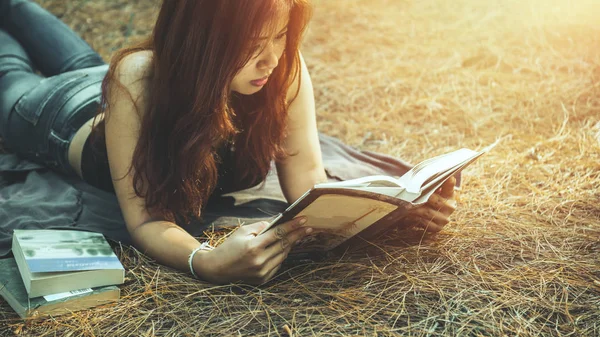Parkta kitap okuyan bir kadın. tatil Uyku dinlenme okuma. Genç kadınlar rahatlar, uyur, tatillerde kitap okur. doğa, açık hava, tatil, eğitim, kitap okumak, kitap, not yaz, günlük.