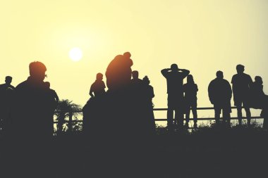 Asyalılar tatilde rahatlarlar. İnsanlar sabahları güneşe bakarlar. Dağda gün doğumu için ayağa kalk