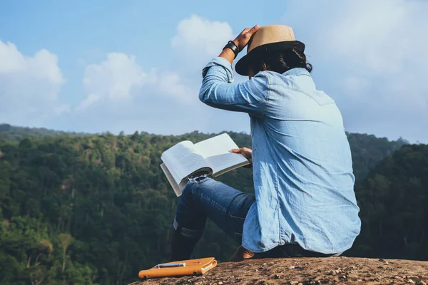 Hombre asiático viajar relajarse en las vacaciones. asientos relajarse leer libros sobre acantilados rocosos. En la montaña. En Tailandia — Foto de Stock