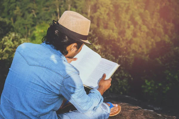 Азиатские мужчины путешествуют отдыхать в отпуске. сидения расслабиться читать книги на скалистых скалах. На горе. В Таиланде — стоковое фото