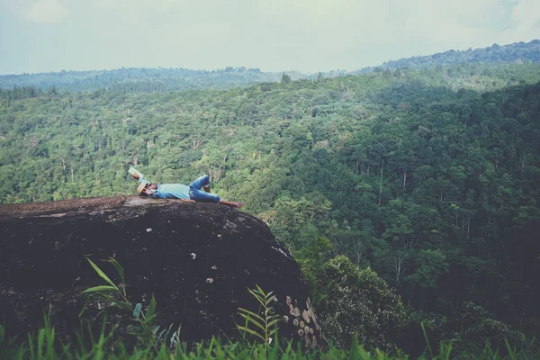 Hombre asiático viajar relajarse en las vacaciones. asientos relajarse leer libros sobre acantilados rocosos. En la montaña. En Tailandia — Foto de Stock