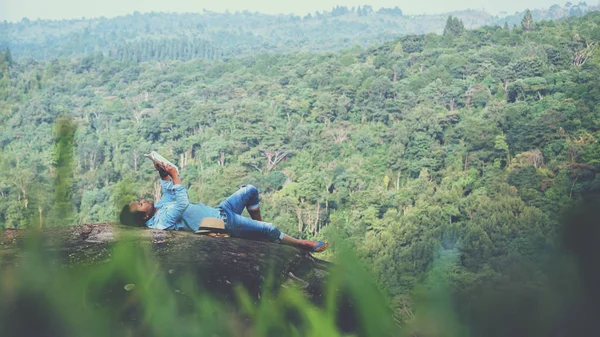 Hombre asiático viajar relajarse en las vacaciones. dormir relajarse leer libros sobre acantilados rocosos. En la montaña. En Tailandia — Foto de Stock