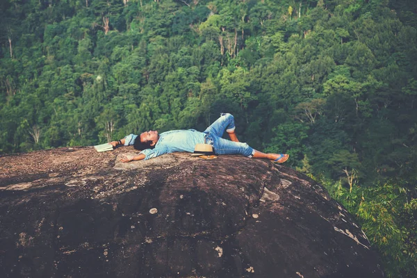 Asian man travel relax in the holiday. sleep relax read books on rocky cliffs. On the Mountain. In Thailand — Stock Photo, Image