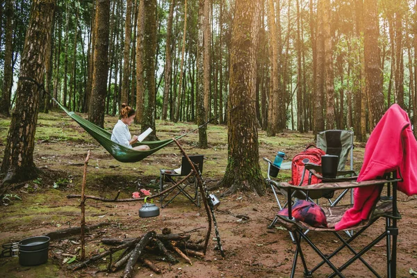 Las mujeres asiáticas viajes naturales relajarse en las vacaciones. sentado leyendo un libro en la hamaca. acampar en el parque nacional Doi inthanon en Chiangmai. en Tailandia — Foto de Stock
