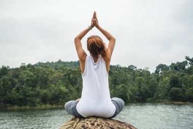 Asyalı kadınlar tatilde rahatlar. Yoga varsa oynayın. Suyun ortasındaki kayalarda