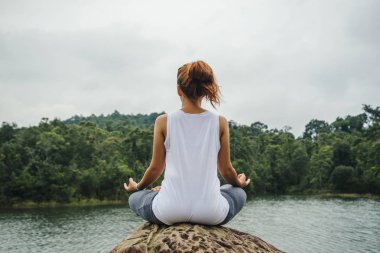 Asyalı kadınlar tatilde rahatlar. Yoga varsa oynayın. Suyun ortasındaki kayalarda