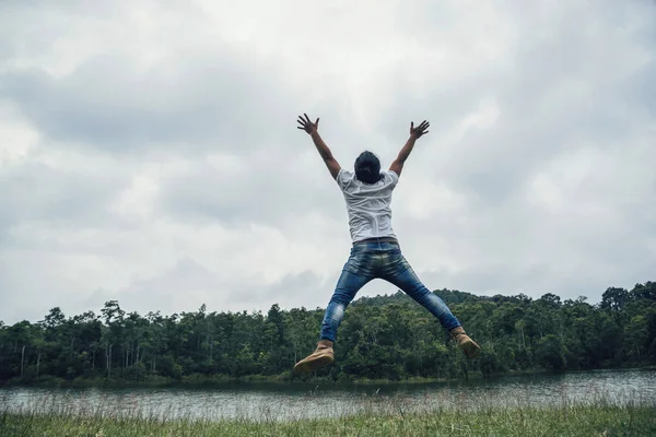 Asyalı adam tatilde rahatlayın seyahat. Yeşil bir çayır üzerine atlamak.
