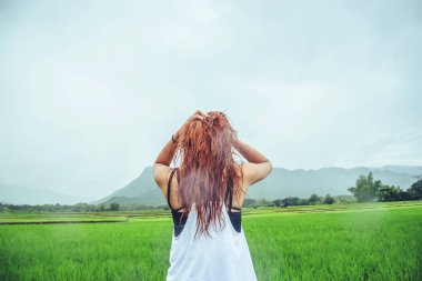 Asyalı kadınlar tatilde rahatlarlar. Yağmurda bir çayırda dur. Çayırda yağmur mevsiminde. Tayland