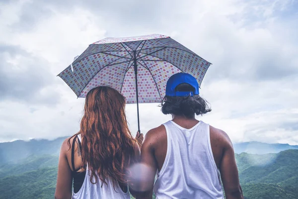 연인 커플 여성과 남성 아시아 여행 휴가에서 휴식. 산에 우산을 쓰고 서 있었다. 장 마 동안. 태국 — 스톡 사진