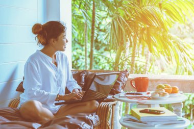 Bir defterle çalışan ve kanepede oturan kadın