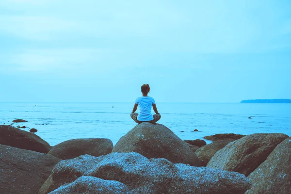 Asian woman travel relax in the holiday. Play if yoga. On the rocks by the sea. — Stock Photo, Image