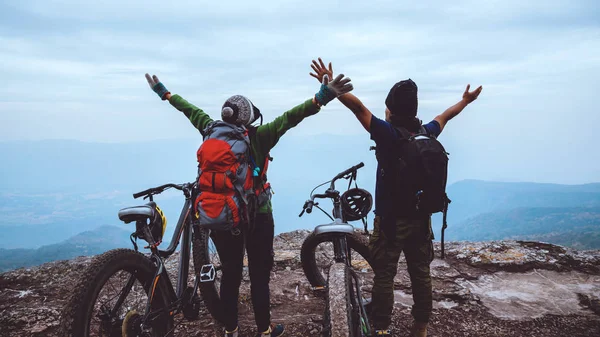 Asian lover woman and man Travel Nature. Travel relax ride a bike Wilderness in the wild. Standing on a rocky cliff. Thailand