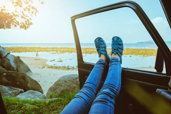 アジアの女性は自然を旅します。夏はビーチでリラックスできます。車の中に座って車の外に海と脚を見て幸せ. — ストック写真