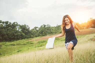 Asyalı kadınlar tatilde rahatlar. yeşil bir mera üzerine bir kitap okuyun