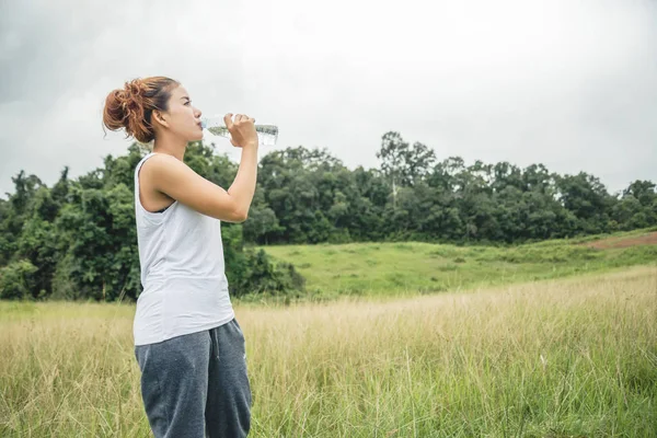Asiatische Frauen entspannen sich im Urlaub. Wasser trinken auf einer grünen Weide — Stockfoto