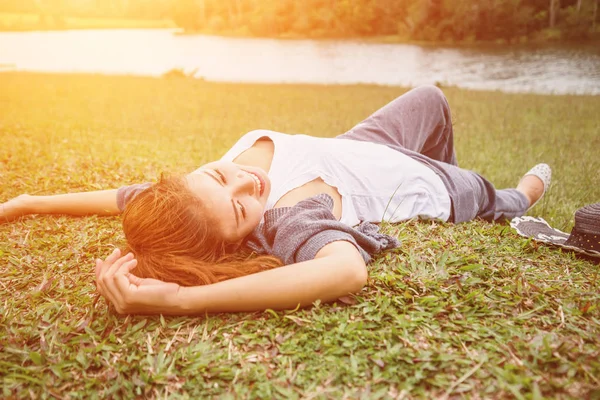 Las mujeres asiáticas se relajan en las vacaciones. dormir relajarse en un pasto verde — Foto de Stock