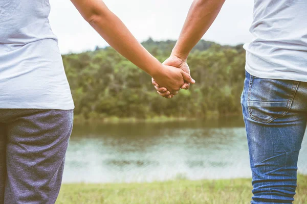 Amante de los hombres y mujeres asiáticos relajarse en las vacaciones. Sostenga las manos caminando pie en el prado — Foto de Stock