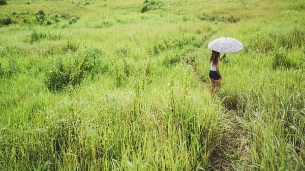 Asijské ženy cestují relaxovat na dovolenou. Běžící slunečník na zelené pastvině. — Stock fotografie
