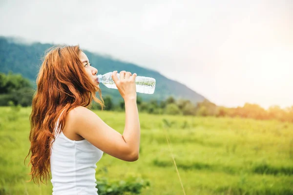 Las mujeres asiáticas viajan relajarse en las vacaciones. Beber agua en un pasto verde . —  Fotos de Stock