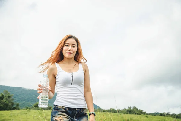 Asiatische Frauen reisen entspannt in den Urlaub. Wasser trinken auf einer grünen Weide. — Stockfoto