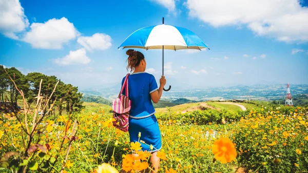 Asian women travel sleep relax. women hill tribe umbrella stand in the field of flowers. Thailand — Stock Photo, Image
