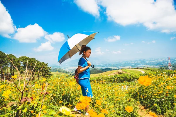 Asiatische Frauen reisen schlafen entspannt. Frauen Hügel Stamm Regenschirm stehen auf dem Feld der Blumen. Thailand — Stockfoto