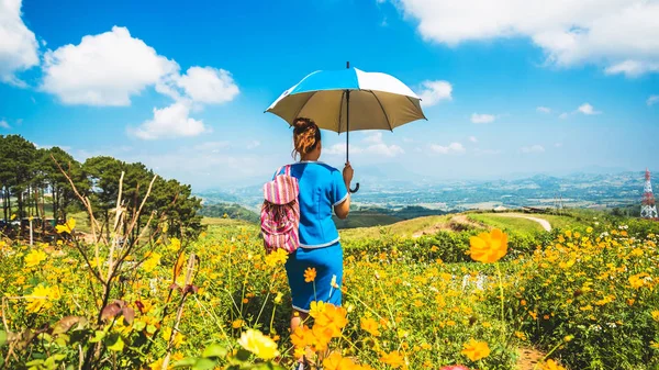 Asiatische Frauen reisen schlafen entspannt. Frauen Hügel Stamm Regenschirm stehen auf dem Feld der Blumen. Thailand — Stockfoto