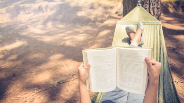 Kadınlar uyurken kitap okuyor. Hamakta. Parktaki doğal atmosferde